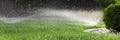 Sprinklers watering grass, green lawn in garden Royalty Free Stock Photo