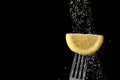 Sprinkling of sugar on lemon slice on dark background