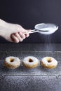 Sprinkling sugar on 3 ring doughnuts