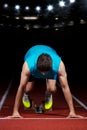 Sprinter leaving starting blocks on the running track in front of big modern stadium with lights. Explosive start. Royalty Free Stock Photo