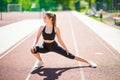 Sprinter woman doing warm-up exercises before run on stadium track with red coating outdoor