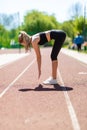 Sprinter woman doing warm-up exercises before run on stadium track with red coating outdoor