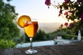 Spritz Veneziano cocktail drink on a garden wall in front of an idyllic landscape, sunset sky with copy space Royalty Free Stock Photo