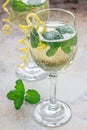 Spritzer cocktail with white wine, mint and ice, decorated with spiral lemon zest