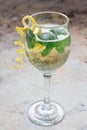 Spritzer cocktail with white wine, mint and ice, decorated with spiral lemon zest