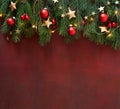 Spruce branch with Christmas decorations on the wooden board  painted in dark-red. Royalty Free Stock Photo