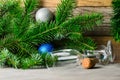 Spruce branches with green needles and Christmas balls on a wooden background. Two empty glasses