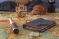 Spyglass, a compass and a leather-bound book lie on an old map against the background of a wooden model of a sailboat. Royalty Free Stock Photo