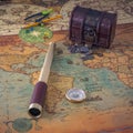 Spyglass and a compass lie on an old map against the background of a forged chest with coins. Royalty Free Stock Photo
