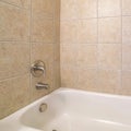 Square Alcove bathtub close up with brown ceramic tiles surround