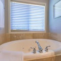 Square Alcove bathtub with tiles surround near the window with blinds