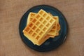 Square baked sweet fluted Belgian waffles on a blue ceramic plate and baggy fabric