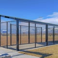 Square Baseball field dugout with slanted roof and chain link fence on a sunny day Royalty Free Stock Photo