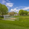 Square Baseball or softball field against lush trees and buildings under cloudy sky Royalty Free Stock Photo