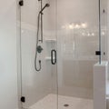 Square Bathroom shower stall with half glass enclosure adjacent to built in bathtub Royalty Free Stock Photo