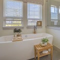 Square Bathtub and shower stall in front of windows with valance and blinds