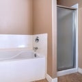 Square Bathtub and shower stall with frosted door inside bathroom with tile floor