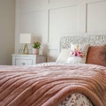 Square Bedroom with feminine beddings and decorative headboard against panelled wall