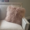 Square Bedroom interior with faux fur throw pillow on a white upholstered armchair