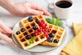 Square belgian waffles with berries and cup of black coffee
