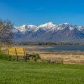 Square Bench on the lush field with a view of a lake and towering snow capped mountain