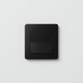 Square black light switch on a plain white wall. The switch features a minimalist design Royalty Free Stock Photo