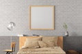 Square blank poster frame mock up on the white brick wall in interior of loft style bedroom Royalty Free Stock Photo