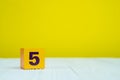 Square block puzzle number 5 on table with yellow background Royalty Free Stock Photo