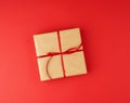Square box wrapped in brown kraft paper and tied with a red thin silk ribbon Royalty Free Stock Photo
