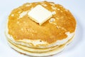 A square of butter laying onto of a stack of golden pancakes on the kitchen table waiting to be eaten Royalty Free Stock Photo