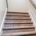 Square Carpeted indoor staircase of home with brown handrail against white side wall Royalty Free Stock Photo