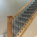 Square Carpeted stairs with wooden handrailing and wrought iron baluster