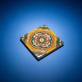 Square ceramic tile on a blue surface featuring an intricate floral pattern Royalty Free Stock Photo