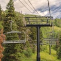 Square Chairlifts against vivid green trees and cloudy sky at Park City in off season