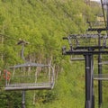 Square Chairlifts on cables over ski mountain with thick green trees during off season