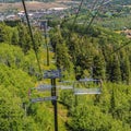 Square Chairlifts over hiking trails and trees on mountain with buildings in Park City