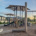 Square Childrens playground at a park with swings slides and umbrellas viewed at sunset Royalty Free Stock Photo