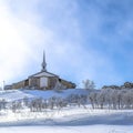 Square Church and homes on a snowy neighborhood landscape against scenic skyscape