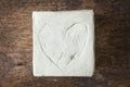 Square with clay heart on wooden surface