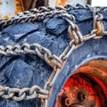 Square Close up of heavy duty black wheels with rusty chains of an old snow bulldozer