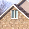 Square Close up of a home exterior with sunlit pitched roof over window and brick wall