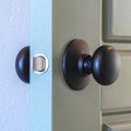 Square Close up of a round black door knob installed on a gray paneled interior door Royalty Free Stock Photo