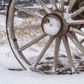 Square Close up of the wooden wheel of an old wagon against a snowy terrain in winter Royalty Free Stock Photo