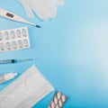 Square composition with medical mask, thermometer, syringe, pills and gloves on a blue background. Copyspace Royalty Free Stock Photo