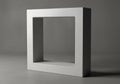 A square concrete frame with a smooth surface sits upright on a gray surface. Its hollow center Royalty Free Stock Photo