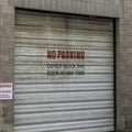 Square Corrugated metal garage door of an old brick building with No Parking sign