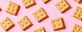 Square crackers on a pink background, flat lay pattern. Snack food concept Royalty Free Stock Photo
