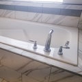 Square crop Close up of built in rectangular bathtub with stainless steel faucet and handles Royalty Free Stock Photo