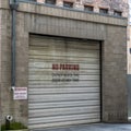 Square crop Corrugated metal garage door of an old brick building with No Parking sign