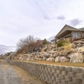 Square crop Dirt road along homes on a slope with huge rocks and concrete retaining wall Royalty Free Stock Photo